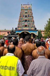 Hindus and a steward on the main festival day at the temple festival in front of the Hindu temple Sri Kamadchi Ampal