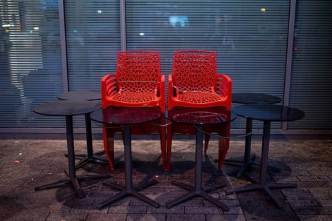 Assembled chairs and tables stand out in front of a closed cafe in Berlin