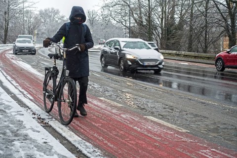 Cyclist walking on foot holding bicycle on slippery bike path