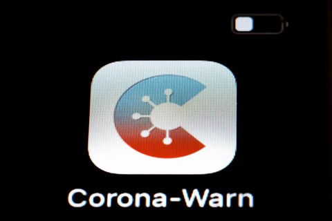 The Corona warning app is displayed on the screen of a smartphone. The app is designed to help trace and interrupt chains of infection of SARS-CoV-2
