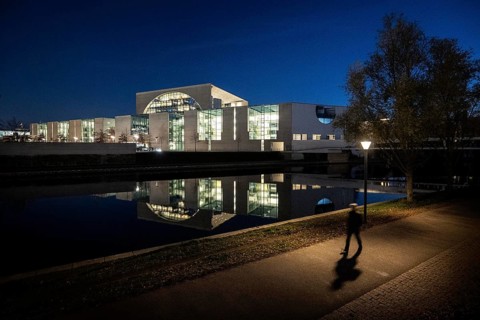 A person stands out in front of the Federal Chancellery at blue hour
