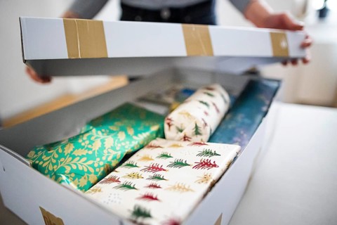 Symbolic photo on the subject of sending Christmas presents by post. A woman opens a parcel with Christmas presents. Berlin
