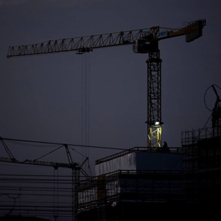 A worker draws on scaffolding and in front of a crane on a newly built house