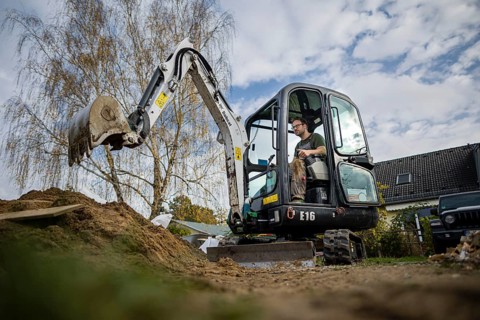 A construction worker sits in a mini-excavator at a building site. Berlin