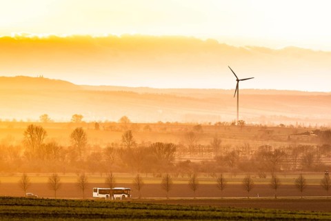 A public bus driving along a country road in the evening light near Oschersleben