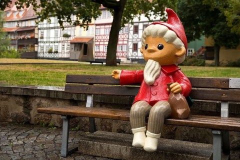 Sculpture of the Sandman on a bench in front of half-timbered houses on Kraemerbruecke in Erfurt