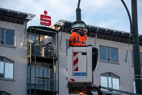 Man in high-visibility waistcoat repairing street lamp