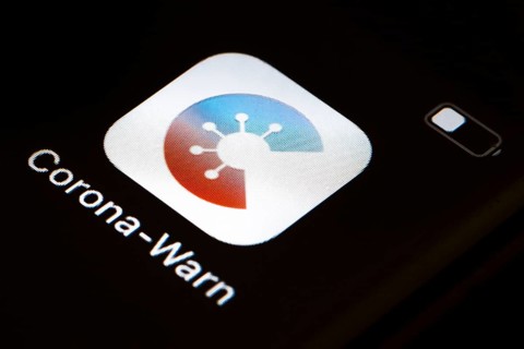The Corona warning app is displayed on the screen of a smartphone. The app is designed to help trace and interrupt chains of infection of SARS-CoV-2