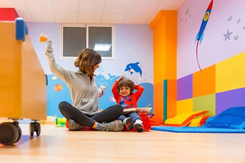 Woman teacher with a child sitting reading a book and expressing things from the story
