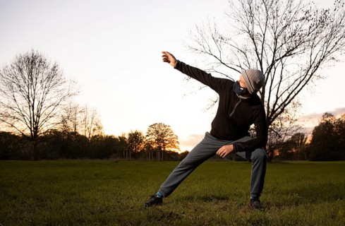 Man with mask stretches in a meadow in autumn.