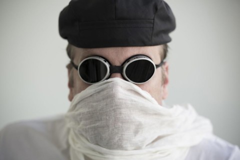 Man with hat and sunglasses and a scarf cover his face