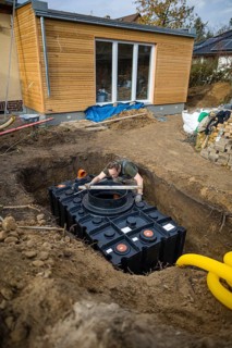 A man installs a water cistern in the garden next to his house to be able to water his garden with rainwater. Berlin