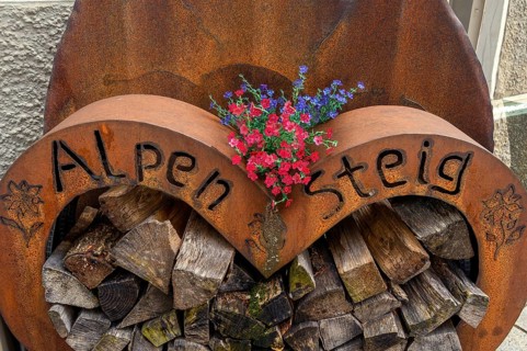 Iron storage container with firewood and geraniums