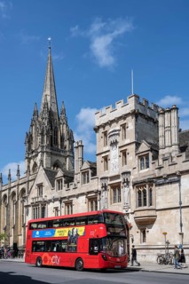 Double decker bus in front of All Souls College on the right and St Mary's Church on the left on the High Street in the Old Town of Oxford