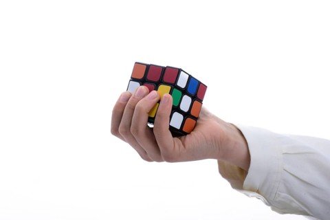 Child holding a Rubik's cube in hand on a white background