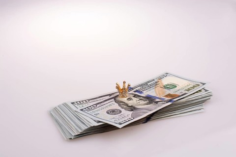 Crown placed on American 100 dollar banknotes on white background