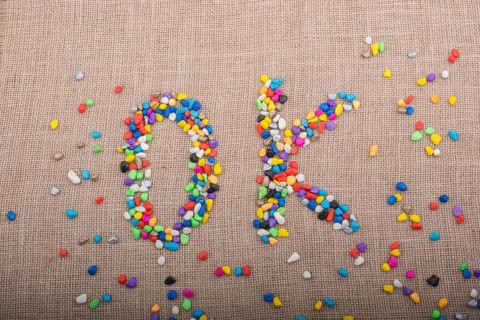 Colorful pebbles form the word OK on canvas ground