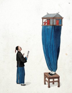 A Chinese puppeteer standing on a stool and balancing a miniature stage above him
