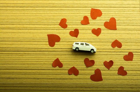 Love concept with model car and heart shaped papers