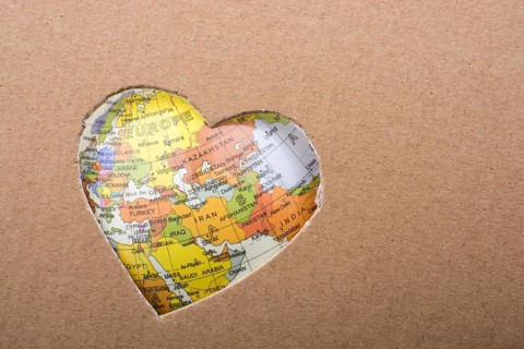 Globe seen through the heart shape hole on paper