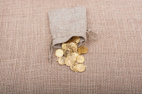 Fake gold coins out of a little sack on canvas