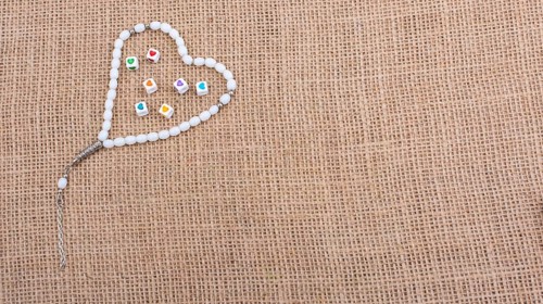 Heart shaped cubes in hand by inside a praying beads