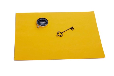 Key and compass on a sheet of colored plain paper with a white background