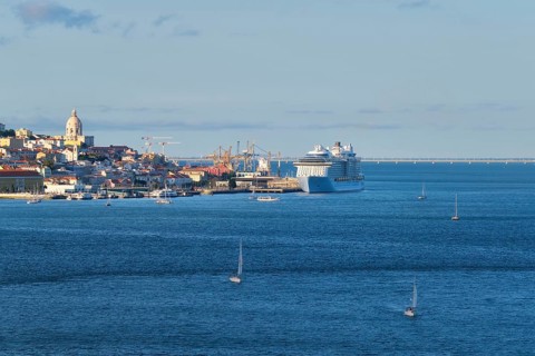 View of Lisbon over Tagus river from Almada with yachts tourist boats and moored cruise liner on sunset. Lisbon