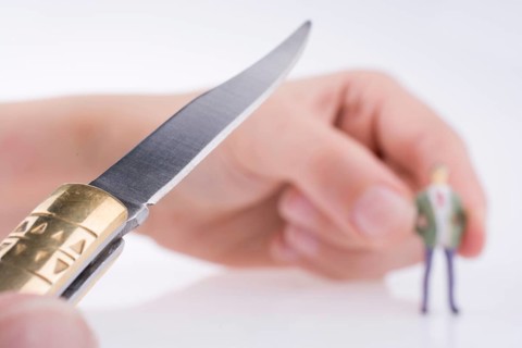 Hand holding a pocket knife near a human figure on a white background