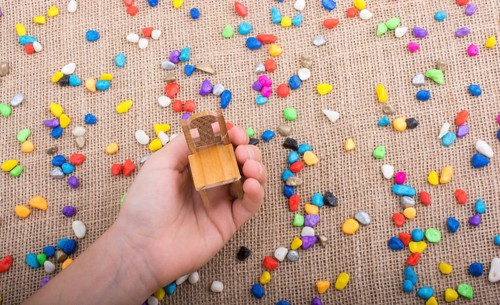 Little chair in hand amid colorful pebbles on canvas
