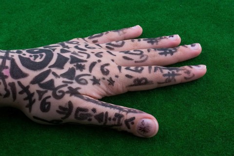 Hand with tattoo on green grass