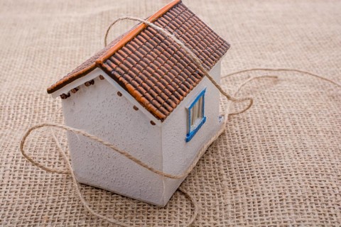 Thread wrapped around a model house on a brown background