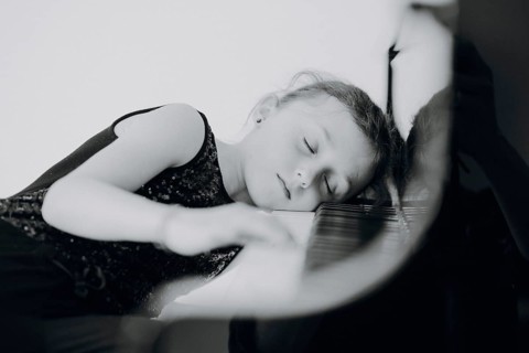Elegant girl sits at the concert grand and plays the piano