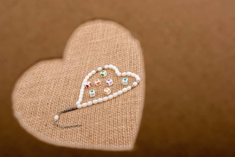Heart shaped gold color metal object in hand