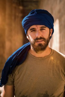 Young man in blue turban walking on the columns of the Edfu Temple near the city of Aswan. Egypt