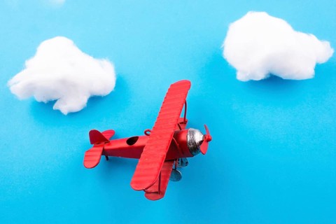 Retro styled little red model airplane in sky