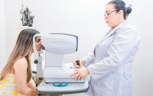 Optometrist checking the eyesight of a patient with an autorefractor. Oculist doing eye exam to female patient