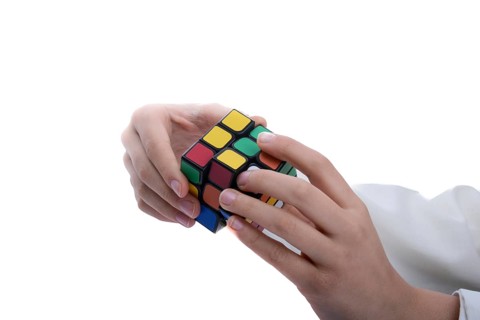 Child holding a Rubik's cube in hand on a white background