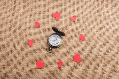 Love concept with pocket watch and paper hearts on threads