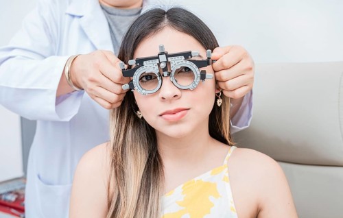 Hands of optometrist examining patient with optometrist trial frame. Young patient with optometrist trial frame