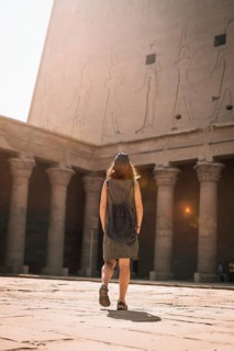 A young tourist wearing a cap visiting the Edfu Temple at sunrise in Aswan. Egypt
