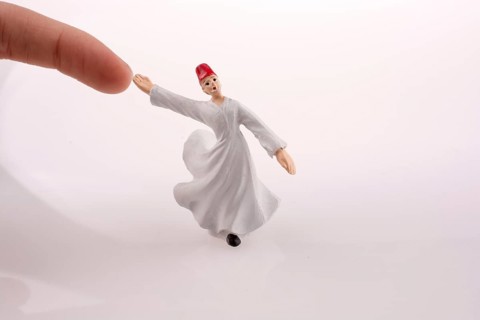 Hand holding a Sufi Dervis on a white background