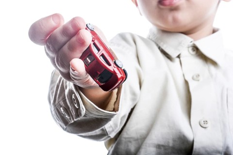 Baby hand holding a red car on a white background
