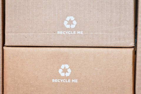 Cardboard boxes with recycling arrow symbol and text saying Recycle me