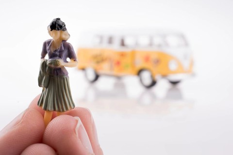 Hand holding a human figure near a peace van on a white background