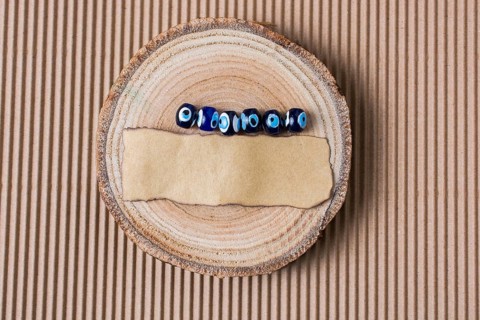 Evil eye beads and piece of burnt paper on wood log