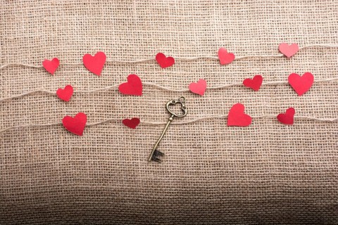 Love concept with heart shaped papers and key on linen threads