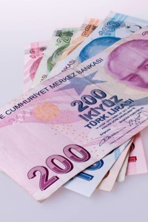 Turkish Lira banknotes by the side of a red color heart shaped object on white background