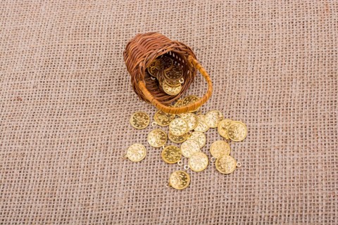 Fake gold coins out of a little basket on canvas
