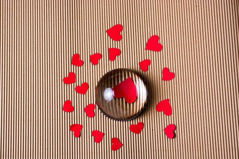 Red color paper hearts under and around half glass globe